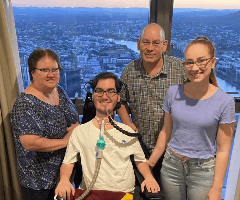 Happy family in front of a window with a beautiful view of Brisbane city and river in the background.